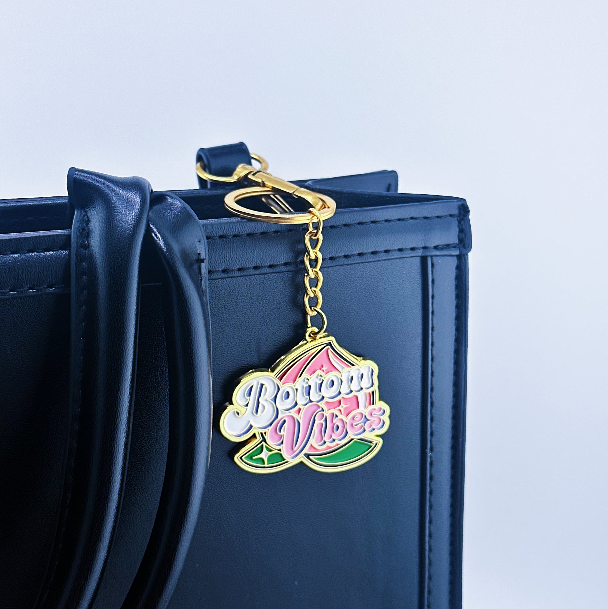 Key Chian has a bottom written in the middle and a big peach on the background, that has been placed on a hand bag.