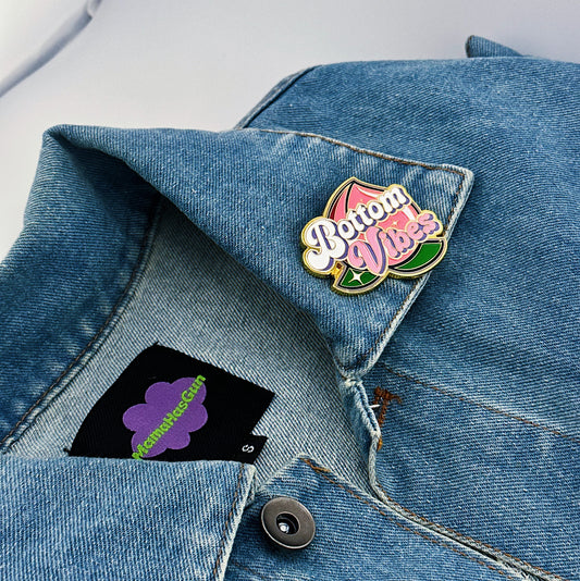 Bottom Vibes Enamel Pin with a big peach on the packground that has been pinned on a jacket.