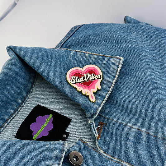 A melting heart enamel pin with slut vibes written in the middle
